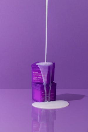 Two purple containers stacked with white liquid pouring over them on a purple background, featuring Nutrition Ampoule Pad | Leaders for skincare and wellness.
