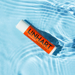 Lip Balm SPF 15 | LINHART spearmint lip balm tube floating in clear blue water, highlighting hydration and skincare benefits.