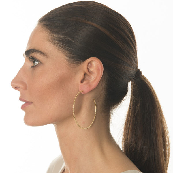 Profile view of a woman with dark hair tied back, wearing large textured gold hoop earrings titled Monte Carlo Hoops (Gold) | Love You More.