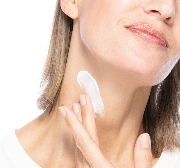 Close-up of a woman applying Necks-Level Smooth™ Cream | Farmhouse Fresh to her neck, demonstrating skincare for smooth, healthy skin.