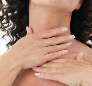 Close-up of a woman gently applying neck cream to smooth skin, highlighting skincare and body care with Necks-Level Smooth™ Cream | Farmhouse Fresh.