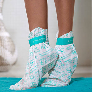 Close-up of feet wearing PoshPeel™ Pedi Cure | Patchology exfoliating foot peel masks on a blue rug for skincare and body care wellness.
