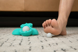 Foot rolling massage on carpeted floor using Neuro Roller | RAD wellness device with textured surfaces and white massage ball for recovery and body care.