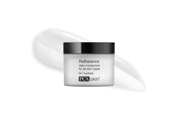 Jar of Rebalance | PCA Skin daily moisturizer for all skin types with a smear of creamy white skincare product behind it on a white background