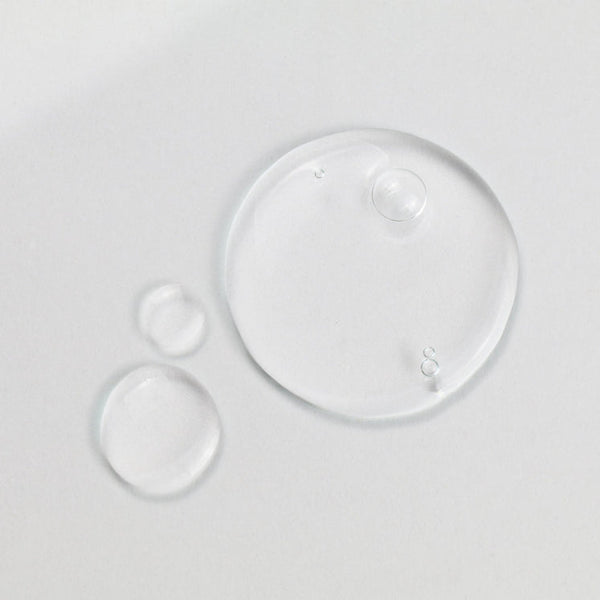 Clear hydration serum droplets on a smooth surface representing the texture of Daily Dose Of Water™ Hyaluronic Acid Hydrating Serum | ClarityRx skincare product.