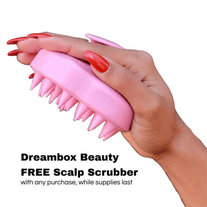 Close-up of a hand holding a pink silicone scalp scrubber designed for scalp massage and exfoliation, featuring the product Scalp Scrubber [Revitalizing Scalp Massager] | Dreambox Beauty.