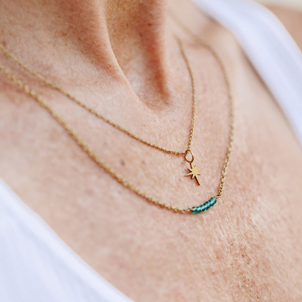 Close-up of a person wearing two delicate gold necklaces, one featuring a small North Star pendant, styled with the North Star Necklace | Purpose Jewelry.