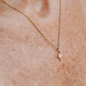 Close-up of a delicate gold North Star Necklace | Purpose Jewelry pendant on a fine chain resting on skin, symbolizing guidance and inspiration.