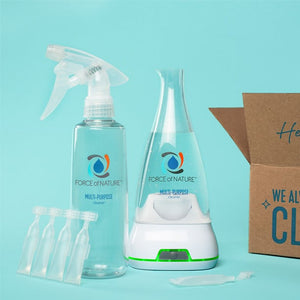12oz Glass Bottle Cleaning Starter Kit | Force of Nature showing a clear multi-purpose cleaner spray bottle, a white and clear base unit, and small clear pods, set against a light blue background with a partially open cardboard box.