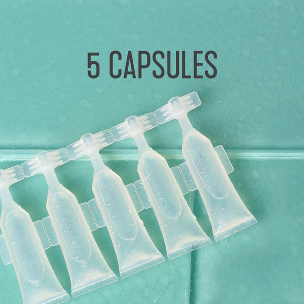 Clear plastic capsules arranged in a row on a teal tiled surface, with the text "5 CAPSULES" above, part of the 12oz Glass Bottle Cleaning Starter Kit | Force of Nature.