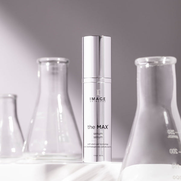 the MAX™ serum | IMAGE Skincare in a sleek silver bottle surrounded by clear laboratory glassware, highlighting skincare innovation and advanced formulation.