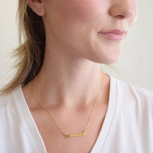 Woman wearing a delicate gold bar necklace with the engraving "Love You More," showcasing the Love You More Bar Gold Necklace | Love You More.