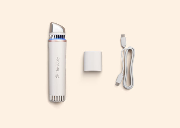 TheraFace Depuffing Wand | Therabody device in white with blue light, charging adapter, and USB-C cable displayed on a light background for skincare and wellness use.