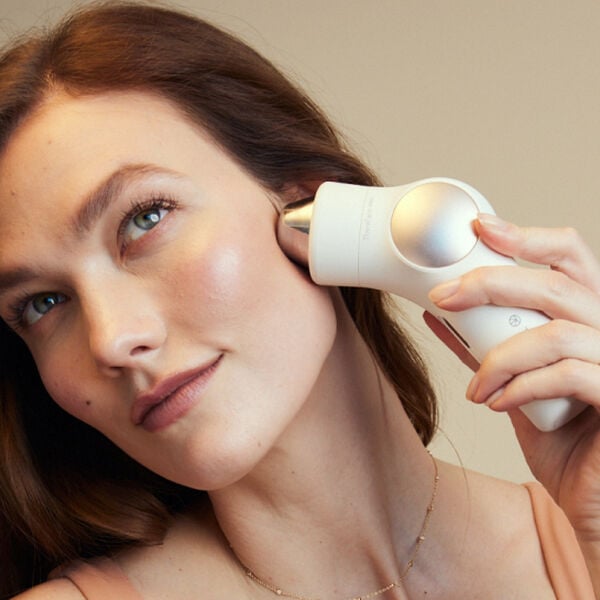 Woman using white Theraface Hot & Cold Rings | Therabody device on her cheek, demonstrating a skincare and wellness recovery tool for facial care.