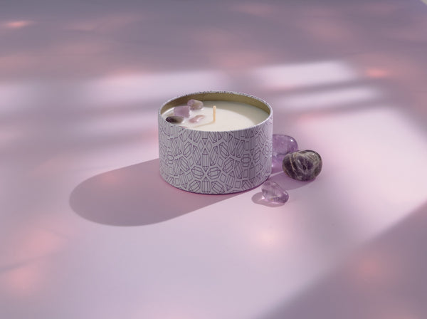Release Candle Tin 6 oz | Aluminate Life with decorative stones resting on a soft pink surface illuminated by gentle natural light, evoking a calm and soothing atmosphere.