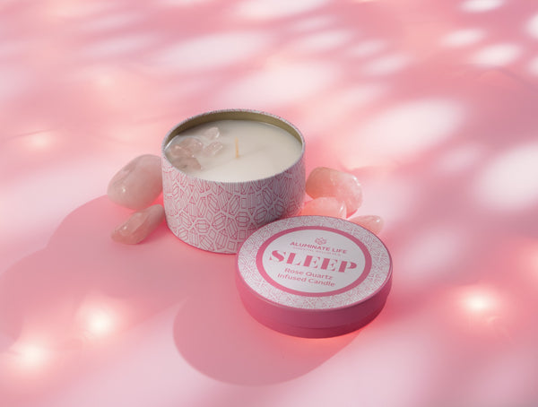 Sleep Candle Tin 6 oz | Aluminate Life with pink patterned tin, surrounded by rose quartz crystals on soft pink background, evoking calm and wellness for relaxation.