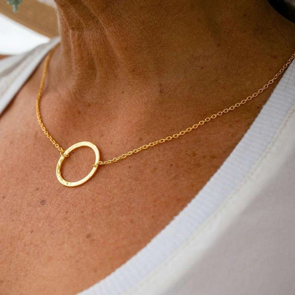 Close-up of a person wearing a delicate gold chain necklace featuring a simple hammered open circle pendant, showcasing the Unity Necklace | Purpose Jewelry design.