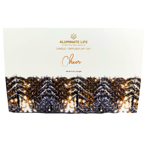Packaging of Candle & Diffuser Set - Cheer | Aluminate Life featuring a white box with festive pine cone design and gold lettering for an essential wellness gift set.