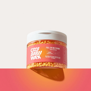 Full On Meltdown Vegan Hard Wax | Crybaby Wax container filled with yellow wax beads, featuring coral and white branding, placed on a gradient orange and pink surface.