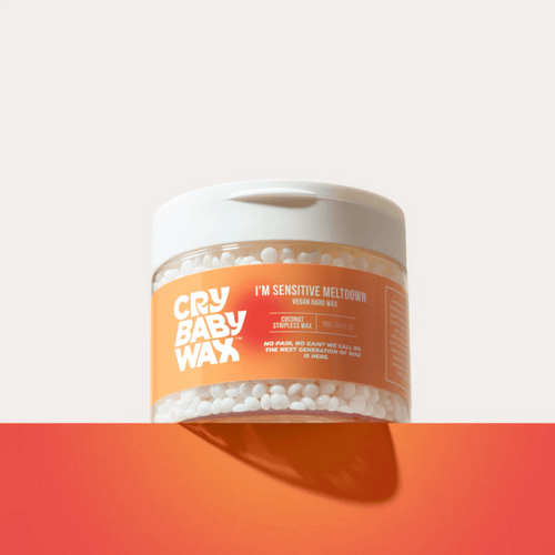 Clear jar of I'm Sensitive Meltdown Vegan Hard Wax | Crybaby Wax with white wax beads inside, featuring an orange label and white lid, placed on an orange surface.