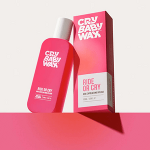 Bright pink bottle and matching box of Ride or Cry AHA Exfoliating Splash by Crybaby Wax displayed on a pink surface with a light background, highlighting skincare product packaging.
