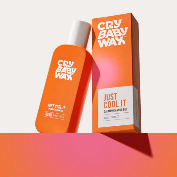 Bright orange bottle and matching box of Just Cool It Calming Mango Gel | Crybaby Wax, a soothing skincare product displayed on a gradient pink and orange surface.