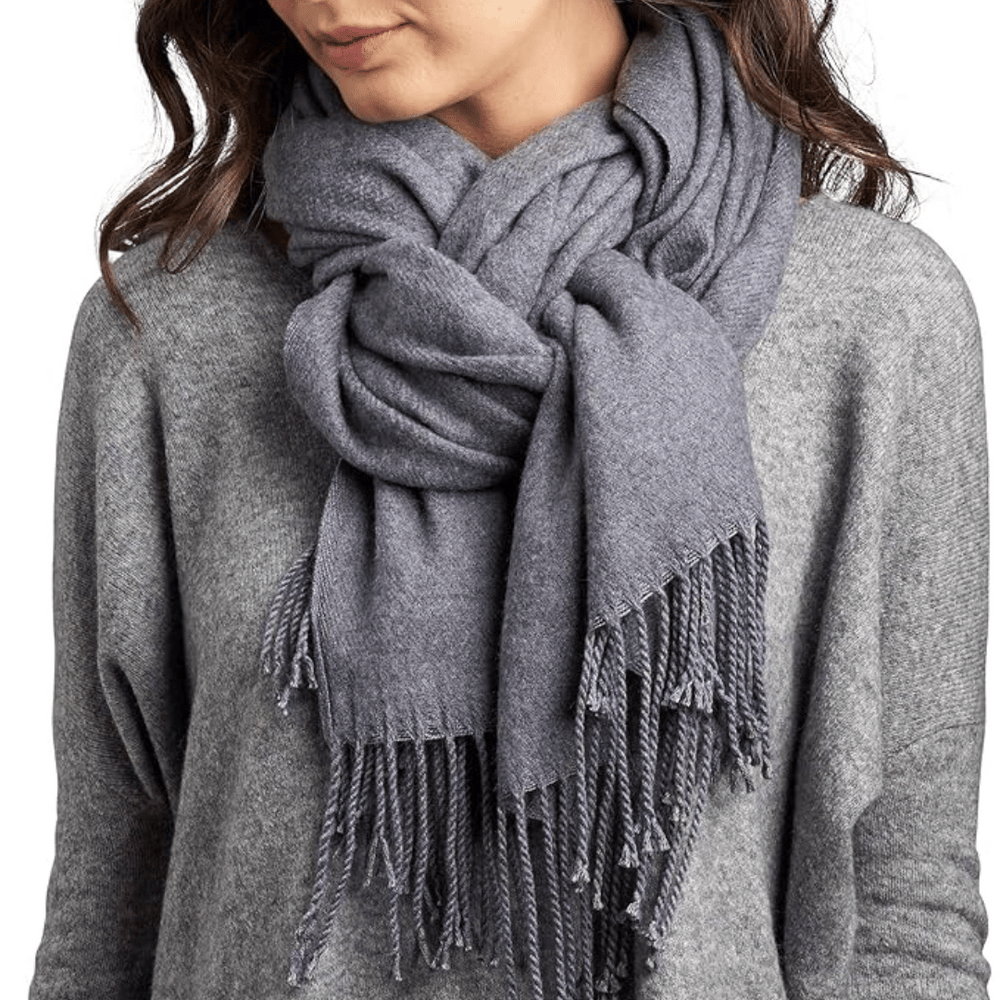 Woman wearing a thick, twisted grey scarf with fringed ends over a grey sweater featuring the product name Twill Cashmere Scarf | Lemon.