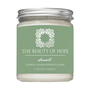 Denali 8oz Candle | The Beauty of Hope with cypress, juniper berries, and pine scent in a clear glass jar with a silver lid, designed for wellness and relaxation.