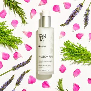 Emulsion Pure Purifying Tonic | Yon-Ka Paris bottle surrounded by fresh green leaves, lavender sprigs, and scattered pink rose petals on a white background, showcasing skincare and wellness.
