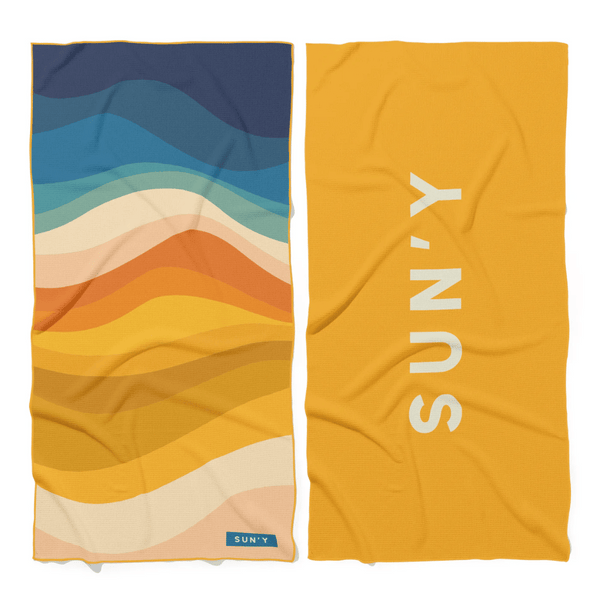 Waffle Microfiber Beach Towel - Boho | SUN'Y with vibrant wavy stripes in blue, teal, cream, orange, and mustard on one side, and solid mustard with SUN'Y logo on the other.