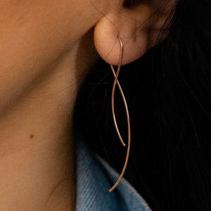 Close-up of a delicate, elegant rose gold wire earring worn on the ear, showcasing the minimalist design of Vista Earrings | Purpose Jewelry.