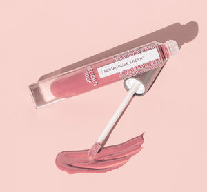 Vitamin Glaze® Oil Infused Lip Gloss – Delicate Rose | Farmhouse Fresh in soft rose shade with applicator wand and swatch of glossy lip color on pink background, showcasing skincare and body care lip product.