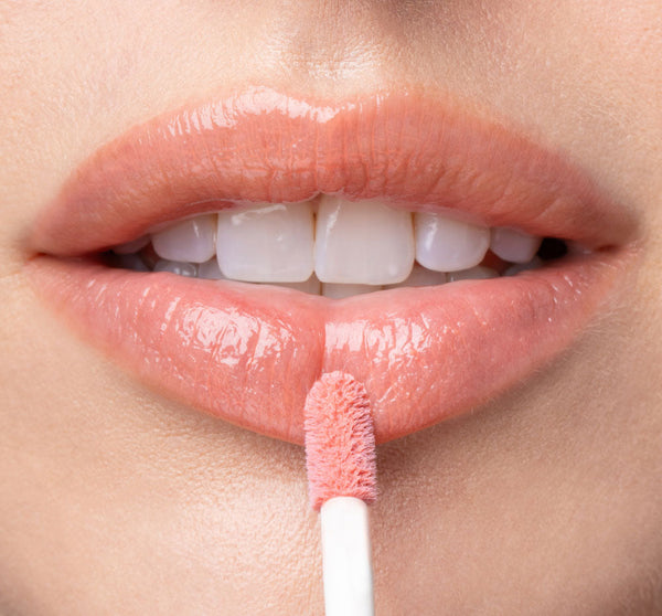 Close-up of lips applying Vitamin Glaze® Oil Infused Lip Gloss – Peach Peony | Farmhouse Fresh with a soft peachy pink shimmer for a glossy, hydrated finish.