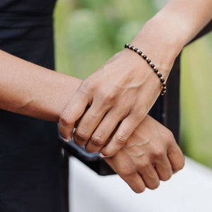 Close-up of a person wearing the Vivid Bracelet | Purpose Jewelry featuring small black and gold beads, showcasing elegant, minimalist style and wellness-inspired design.