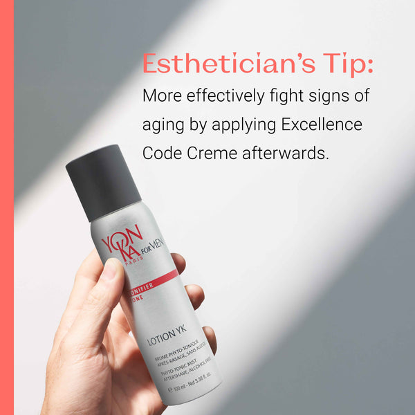Hand holding a bottle of Men’s Lotion YK - Phyto-Tonic Aftershave I Yon-Ka Paris with a tip recommending applying Excellence Code Creme to more effectively fight signs of aging.