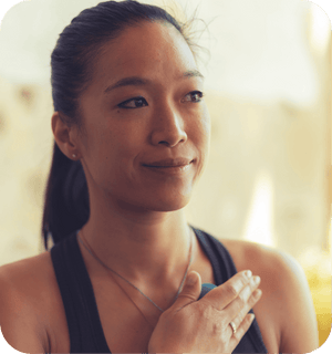 Woman holding a wellness device to her chest with a calm expression, promoting mindfulness and self-care with the RAD All In Kit | RAD.
