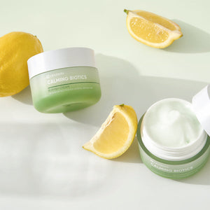 Calming Biotics Blemish Cream | Leaders in green jars with white lids, shown alongside fresh lemon slices, highlighting a natural skincare product for blemish care and soothing skin.