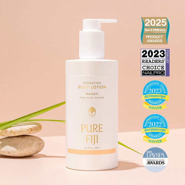 Hydrating Body Lotion | Pure Fiji bottle with pump dispenser displayed alongside spa stones and green leaves, featuring multiple wellness and skincare award badges.