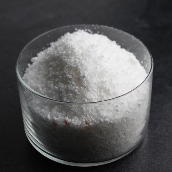 A clear glass bowl filled with coarse white salts, representing Detox Bubbling Bath Salts | Primal Elements, highlighting natural skincare and body care wellness.