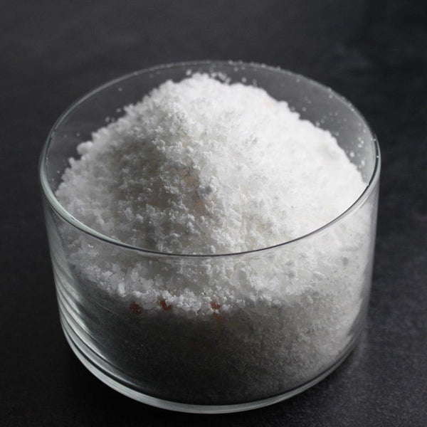 Close-up of white granular Lavender Bubbling Bath Salts | Primal Elements in a clear glass container, highlighting texture and purity for body care and wellness relaxation.