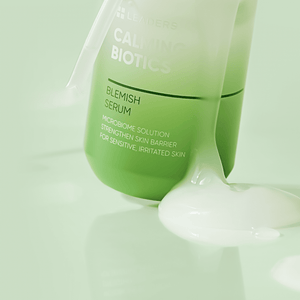 Green bottle of Calming Biotics Blemish Serum | Leaders with a white creamy serum spilled around it, highlighting skincare for sensitive and irritated skin.