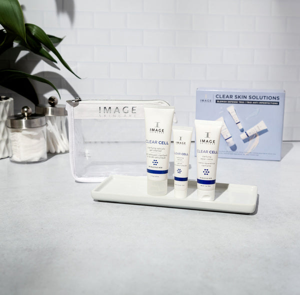 CLEAR SKIN SOLUTIONS Blemish Defense Trio | IMAGE Skincare displayed with three skincare tubes on a white tray, a clear cosmetic bag, and the product box in a bright, clean setting.