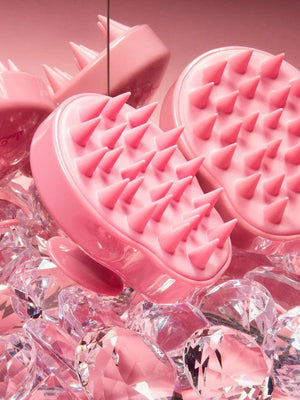 Pink silicone scalp scrubbers with soft flexible spikes, resting on clear crystals, highlighting the Scalp Scrubber [Revitalizing Scalp Massager] | Dreambox Beauty for wellness and skincare.