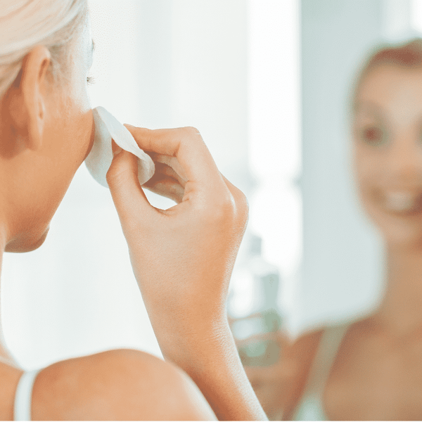 Person using a cotton pad to apply Gentle Mineral Toner - Infused w/ Rose Quartz | Privai on their face, reflecting a skincare routine focused on wellness and self-care.