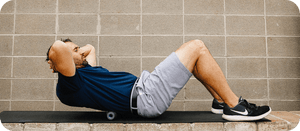 Man in athletic clothing using a small fitness recovery device under his upper back while lying on a bench, demonstrating RAD HELIX | RAD for muscle relief and wellness.