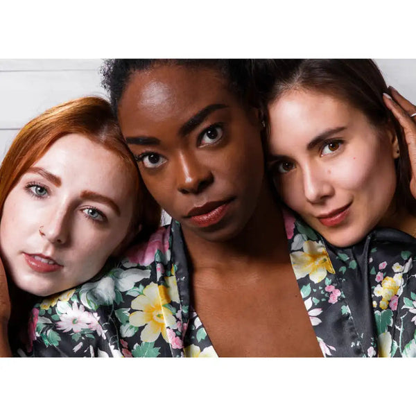 Three diverse women wearing floral robes showcasing natural makeup looks featuring Le Lip Tint | French Girl, emphasizing inclusive beauty and skincare confidence.