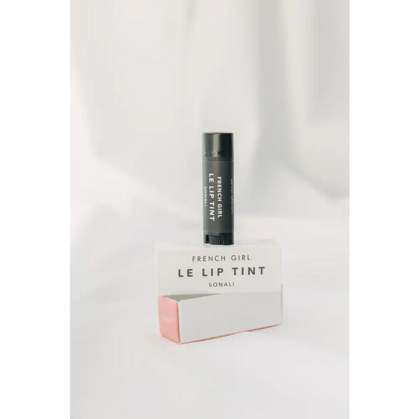 Le Lip Tint | French Girl in black tube packaging standing on a white and light pink box with minimalist design on a soft white background.