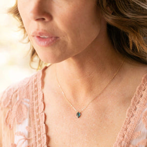 Woman wearing a delicate necklace featuring a teal kyanite pendant on a sterling silver chain captioned as Insightful Teal Kyanite Sterling Silver Necklace | Liv & B.