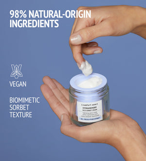 Hand holding an open jar of Hydramemory Rich Sorbet Cream | [ comfort zone ] with a dollop of cream on fingers, highlighting 98% natural-origin ingredients, vegan formula, and biomimetic sorbet texture for skincare.