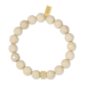 Natural Fossil Stone Beaded Stretch Bracelet | Meghan Bo featuring polished beige fossil stone beads with a gold-tone crystal-encrusted accent bead and a branded gold tag for a chic wellness accessory.